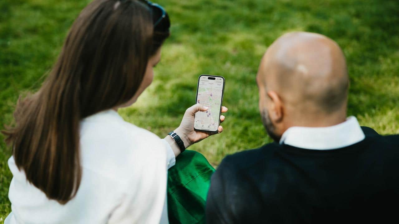 2 personer tittar på en telefon med Hemnets app öppen